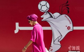 行人从卡塔尔世界杯吉祥物“拉伊卜”的海报前走过